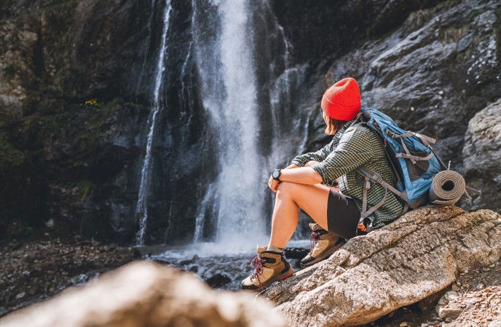 mujer sentada en una roca cerca de una cascada